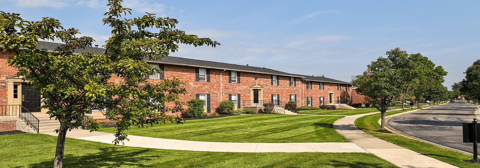 a brick building with green grass and trees in front of it